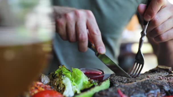 Essen in Nahaufnahme, Mann schneidet Fleischsteak mit Messer — Stockvideo