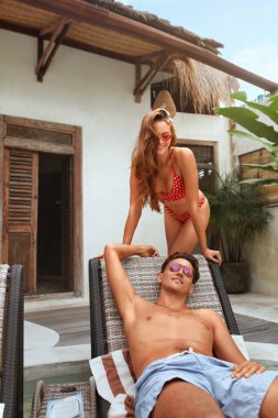 Bilardoda aşık bir çift. Yaz tatilindeki yakışıklı erkek ve güzel kadının portresi. Erkek ve kadın balayının tadını çıkarıyor ya da Tropikal Villa 'da romantik bir hafta sonu. Mutluluk İçin Tatil Merkezinde Dinlenme.