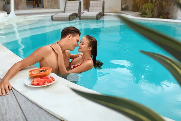 Ett par i poolen. Man och kvinna kommer att kyssa varandra på turkost vatten bakgrund. Man och kvinna på sommarsemester i Tropical Villa. Smekmånad eller romantisk helg på Resort. — Stockfoto