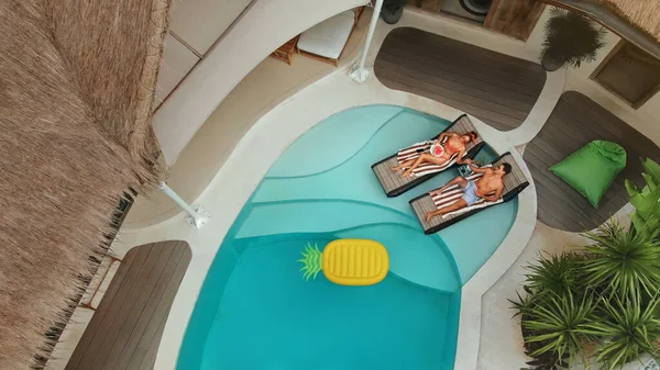 Férfi és nő a medencénél. Top View Of Couple In Love Élvezi Nyári vakáció Villa. Jóképű srác és gyönyörű lány gyümölcsöt esznek és lazulnak a medencénél. Szabadidő a napfényen szék a nászút alatt. — Stock Fotó