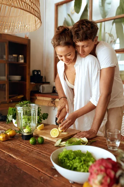 Homme et femme cuisinent ensemble à la cuisine. Couple romantique coupe citron pour préparer Cocktail de désintoxication. Fruits et légumes biologiques frais pour Smoothie. Vitamines naturelles pour une alimentation saine. — Photo