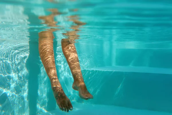 Bajo el agua. Mujer manteniendo las piernas en la piscina mientras está sentado en la piscina. Mujer disfrutando de agua turquesa y ocio en el Resort. Recreación en vacaciones de verano. — Foto de Stock