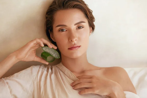 アロエベラスライスと女性の美しさの肖像画.完璧な成長と水分を含んだ肌を持つ美しいモデル。カメラを見ると自然のメイクで公開ブレット。SPA療法のための有機化粧品. — ストック写真
