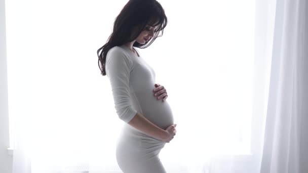 Embarazada mujer tocando bebé vientre en blanco interior — Vídeos de Stock