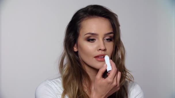 リップスキンケア。唇にバルサムを適用する美容メイクを持つ女性 — ストック動画