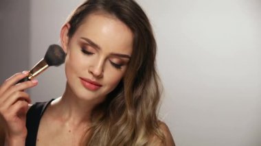 Yüz makyajı. Gülümseyen Kadın Cildine Pudra Uyduruyor