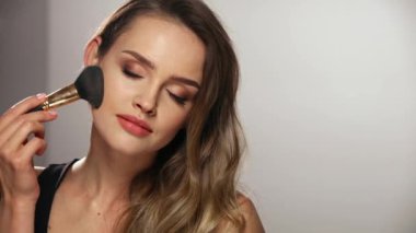 Yüz makyajı. Gülümseyen Kadın Cildine Pudra Uyduruyor
