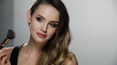 Yüz makyajı. Gülümseyen Kadın Cildine Pudra Uyduruyor