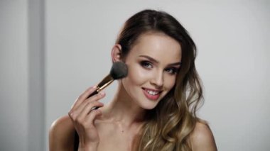 Güzel makyajlı kadın yüz pudrası kullanıyor.