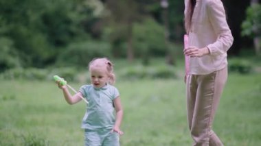 Doğada eğlenen çocuk. Kız dışarıda sabun köpüğü yapıyor.