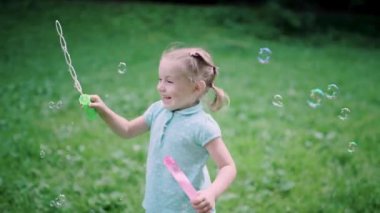Doğada eğlenen çocuk. Kız dışarıda sabun köpüğü yapıyor.