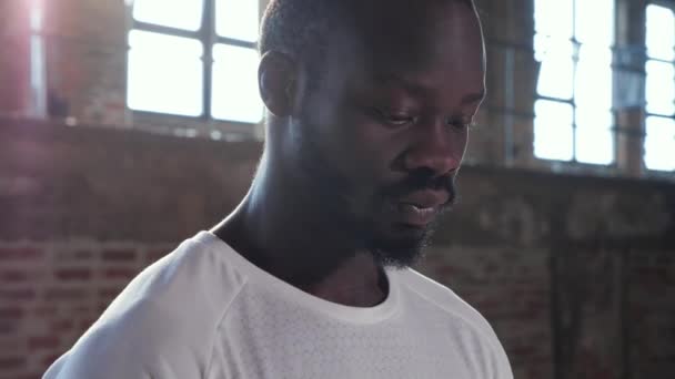 Retrato de hombre negro en camiseta blanca mirando a la cámara interior — Vídeo de stock