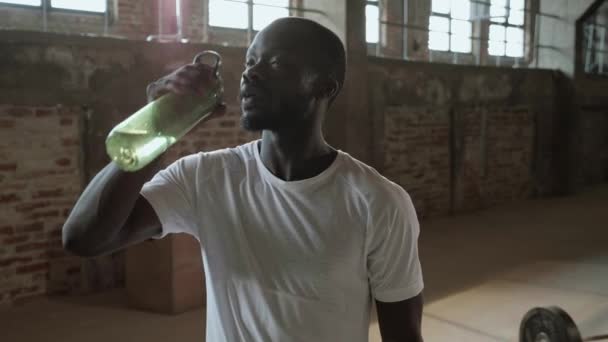 Hombre beber agua de la botella de deporte después del entrenamiento en el gimnasio — Vídeo de stock