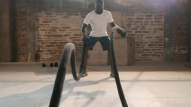 Spor adamı spor salonunda halat egzersizi yapıyor.