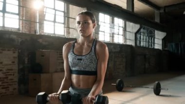 Formda bir kadın spor salonunda ağırlık egzersizi yapıyor.