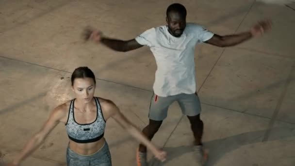 Sprawność. Pasująca para robi skoki jack ćwiczenia na siłowni w pomieszczeniach — Wideo stockowe