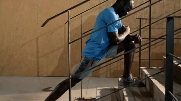 Ajuste o homem esticando as pernas, fazendo exercício lunge nas escadas — Vídeo de Stock