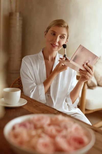 Mulher Aplicando Maquiagem. Retrato de mulher sentada no quarto e usando escova cosmética. Senhora em seda pijama tendo manhã beleza rotina. — Fotografia de Stock