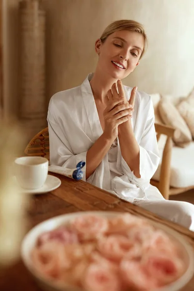 Kobieta nakładająca krem do rąk. Portret kobiety w jedwabnej piżamie w domu. Pielęgnacja skóry Rutyna jako część piękna Anti-Aging i przeciwzmarszczkowe terapii rano. — Zdjęcie stockowe