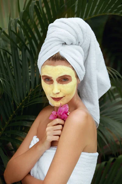 Huidverzorging. Een vrouw met een geel kleimasker op haar gezicht. Vrouw in bad handdoek na het aanbrengen van Beauty Product met kurkuma. SPA behandeling en anti-veroudering therapie voor perfecte gezichtsbehandeling Derma. — Stockfoto