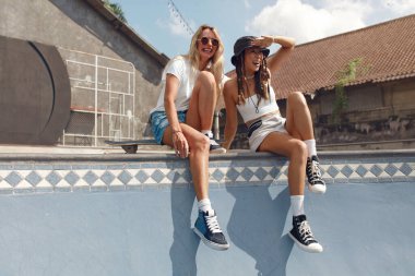 Yaz. Paten parkında Beton Rampada Patenci Kızlar eğleniyor. Dişi hippiler açık havada kaykay kıyafetleriyle dolaşıyorlar. Kentsel Alt Kültür ve Kaykay Şehirde Yaşam Tarzı.