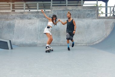 Paten parkında bir çift. Kaykayla gezen sıradan giysili mutlu adam ve kız. Şehir Altkültürü olarak Ekstrem Spor ve Kaykay. Şehirdeki Aktif İnsanların Yaşam Tarzı.