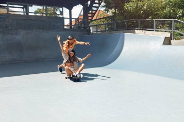 Yaz Eğlencesi Paten Pisti. Kaykayla gezen sıradan giysili mutlu adam ve kız. Şehirdeki Olağanüstü Spor Şehir Halkının Yaşam Tarzı. Aktif Arkadaşlar İçin Kaykay Hobisi.