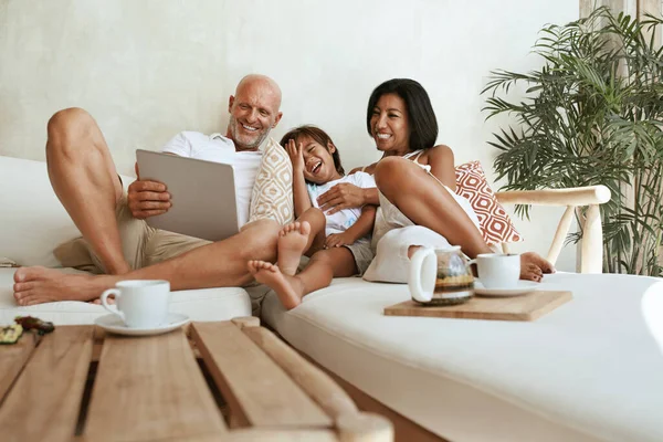 Diversão em família em casa. Pai, mãe e menino sentados no sofá na sala de estar com tablet. Os pais bebem chá, usando dispositivo digital portátil e desfrutando de lazer no fim de semana. — Fotografia de Stock
