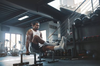 Spor salonu. Sporcu, L-Sit Abs antrenmanı için Parallettes kullanıyor. Asyalı adam içeride spor aletleriyle egzersiz yapıyor. Güçlü, sağlıklı, kaslı, seksi adamın portresi..