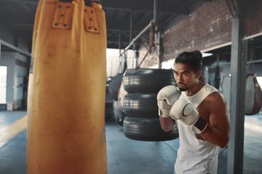 Adam Yumruk Torbası. Asyalı sporcu, yoğun antrenmanda boks yapıyor. Güçlü, sağlıklı ve kaslı vücut için beden eğitimi. Seksi Adam Spor Malzemeleri Kullanıyor.