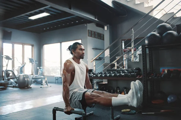 Entrenamiento. Hombre con paraletas haciendo ejercicio en el gimnasio. Culturista masculino asiático que utiliza el equipo de acero del deporte para el entrenamiento de los Push-Ups. Deportista sexy con cuerpo fuerte, saludable y muscular. Fitness como estilo de vida. — Foto de Stock