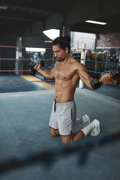 健身房。拳击台上带着哑铃的人练习.赤身裸体的亚洲运动员在健身中心练地板。室内肌体训练的无袖性感帅哥的肖像. — 图库照片