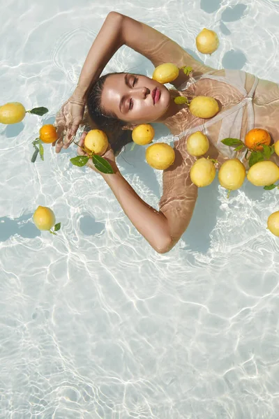 Моделі Портрет в басейні з Цитрусом. Красива дівчина плаває на воді зі свіжими тропічними фруктами в SPA . — стокове фото