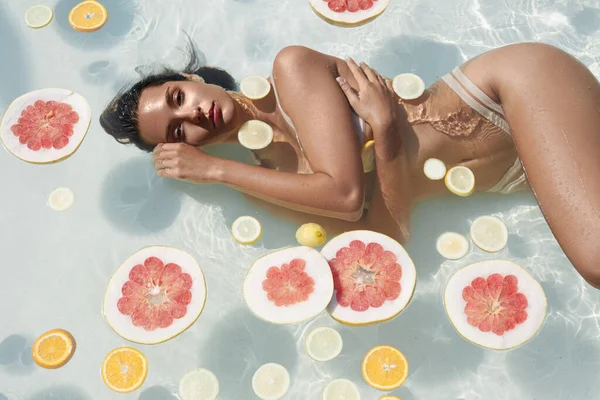 Beau portrait de filles dans la piscine avec des agrumes. Femme en bikini profitant d'une journée ensoleillée au SPA Resort. — Photo
