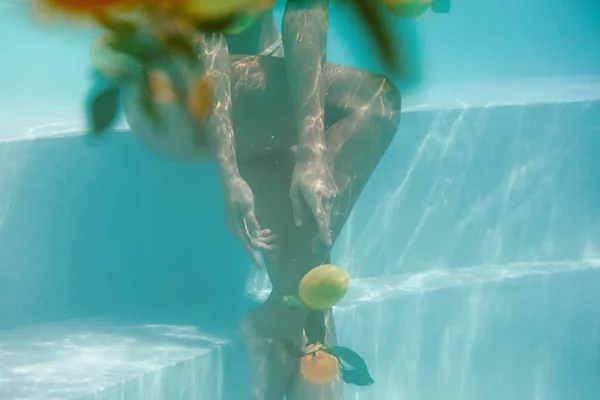 Cuerpo bajo el agua. Hermosa mujer posando en la piscina con cítricos. Sexy modelo delgado en bikini en SPA. — Foto de Stock