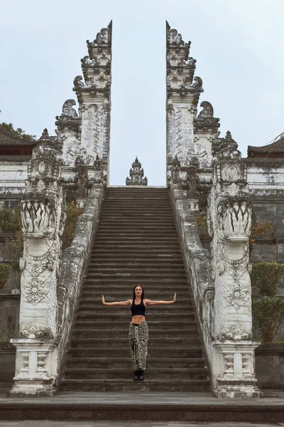 Menina bonita de pé com braços abertos em escadas de pedra para portas do céu em Pura Lempuyang Templo em Bali, Indonésia. Jovem feliz explorar arquitetura antiga em Karangasem, Ásia. — Fotografia de Stock