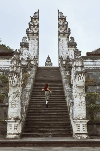 Mujer joven subiendo escaleras de piedra a las puertas del cielo en el templo de Pura Lempuyang en Bali, Indonesia. Hermosa chica camina y explora la arquitectura antigua en Karangasem, Asia. — Foto de Stock