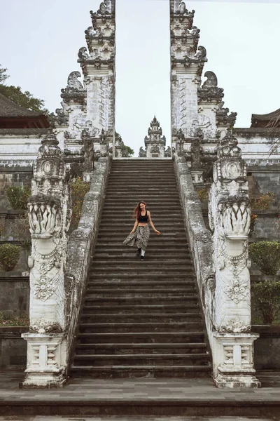 Hermosa chica bajando escaleras de piedra de las puertas del cielo en el templo de Pura Lempuyang en Bali, Indonesia. Mujer joven y feliz explora famoso hito en Asia. — Foto de Stock