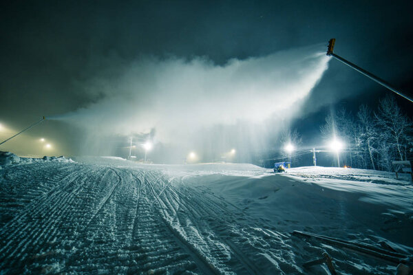 Snow bombers producing snow in night at Alps mountains, Italy.