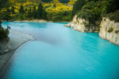 Kayalar ve ağaçlarla çevrili parlak mavi nehir