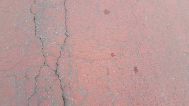 Kırmızı renkli hasarlı yol ya da farklı şekillerde çatlaklarla döşenmiş asfalt yol. Metin ve iletiler için kopyalama alanı olan çatlak doku