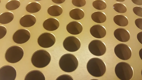 Close up view of holes in golden micro pipette box in research laboratory