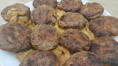 Lezzetli baharatlı kızarmış yuvarlak kebap ahşap zemin üzerinde beyaz seramik plaka servis