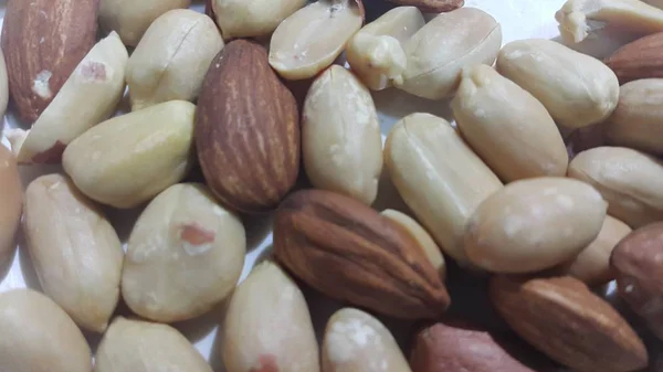 Cacahuetes secos y tostados y almendras sin cáscara. Una fruta para el fondo — Foto de Stock