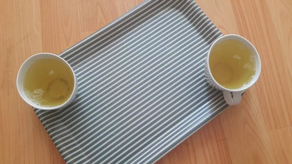 Vue du dessus du thé vert dans une tasse placée dans un plateau au-dessus d'un plancher de bois — Photo