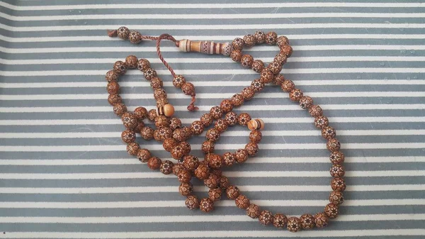 Hermosas cuentas de oración de madera o rosario con un fondo rayado — Foto de Stock