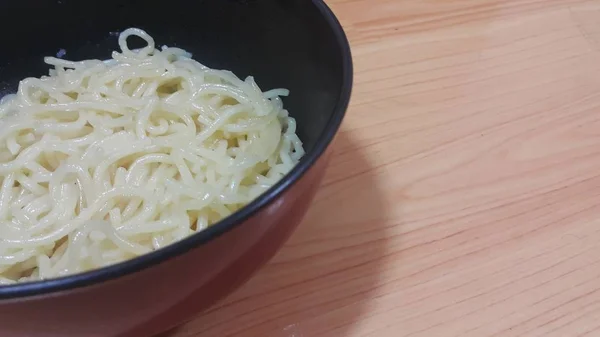 Vista ravvicinata di tagliatelle vorticose o spaghetti in una ciotola sul pavimento in legno — Foto Stock