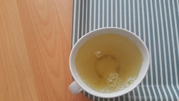 Vue du dessus du thé vert dans une tasse placée dans un plateau au-dessus d'un plancher de bois — Photo