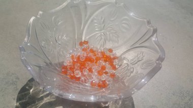 Cam bir kapta parlayan, şeffaf, turuncu renkli kristal boncuklar veya değerli taşlar