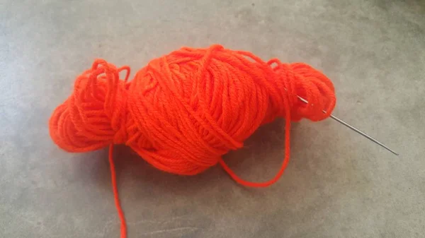 Оранжевый шар из ниток тканой пряжи для вязания на сером фоне пола — стоковое фото